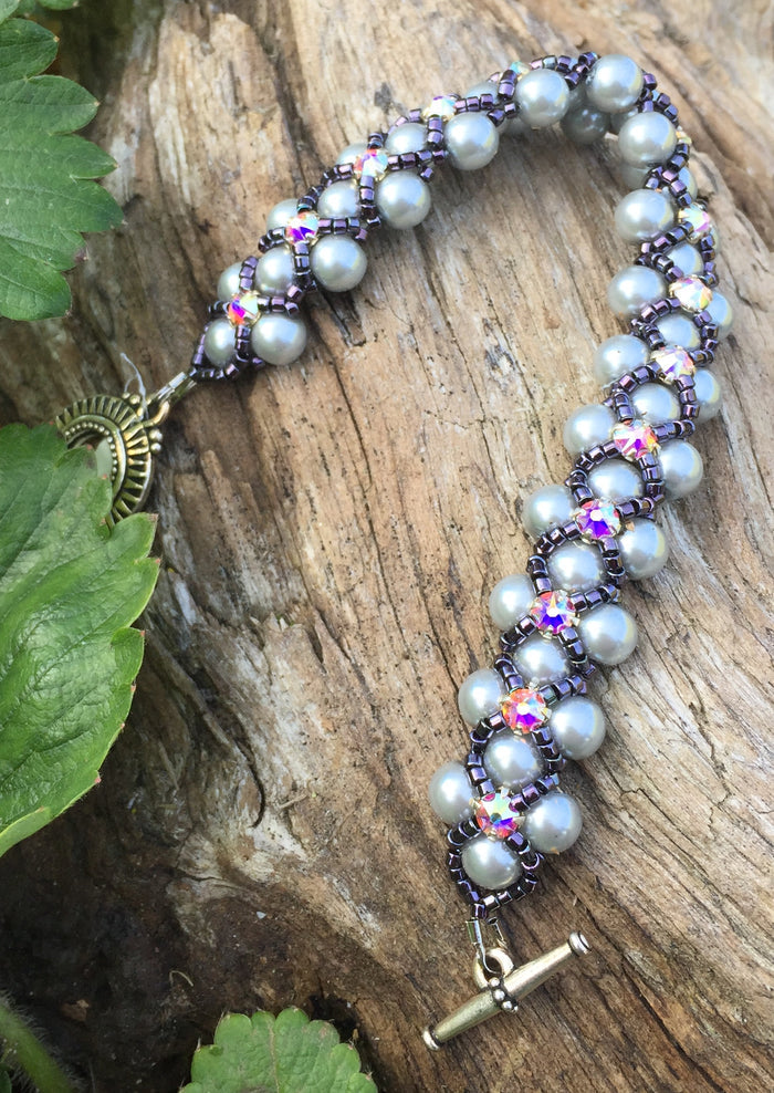 This Silver glass pearl and Dark Purple Delica Seed Bead bracelet is topped with Swarovki Crystal Montees and measures 7 1/4".