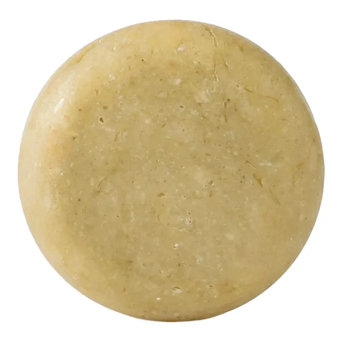 A round, solid bar of soap with a textured surface in a light tan colour, isolated on a white background.