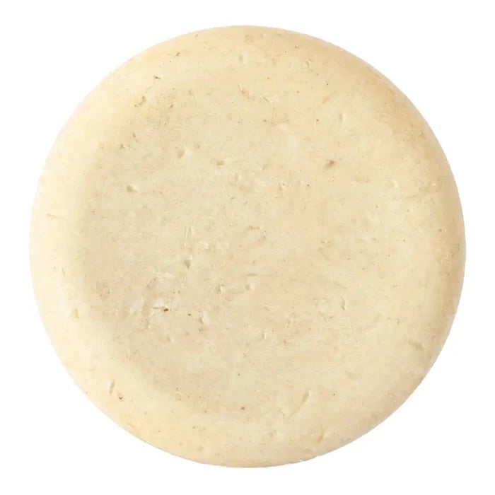 A round, off-white soap bar, shown from a top-down view on a solid white background.